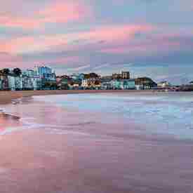 Sunset at Viking Bay, Broadstairs with pink and purple sky and waves across the beach